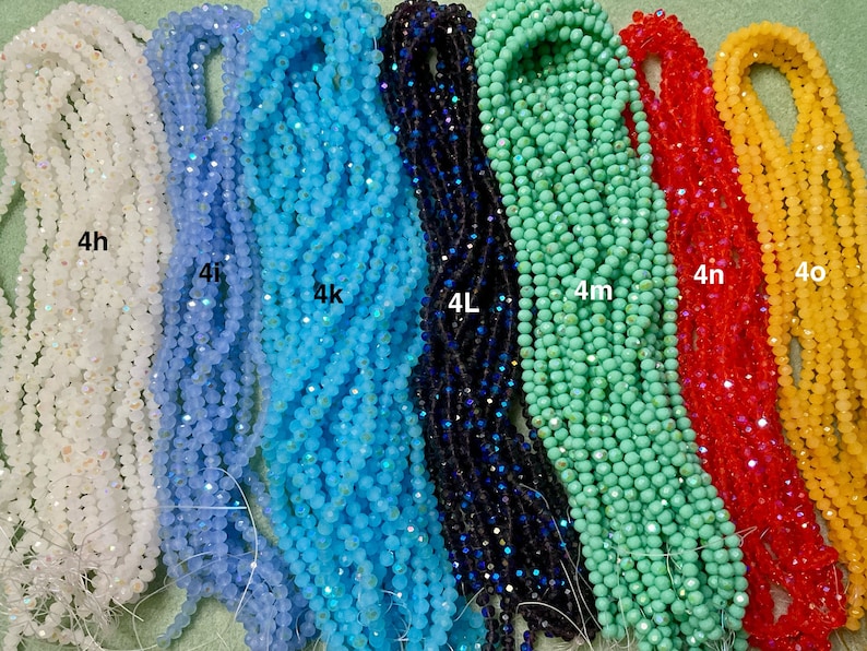 May include: Assortment of 10 strands of crystal beads in various colours, including white, light blue, turquoise, dark blue, green, red, and yellow. Each strand is labelled with a letter and number, such as 4h, 4i, 4k, 4L, 4m, 4n, and 4o.