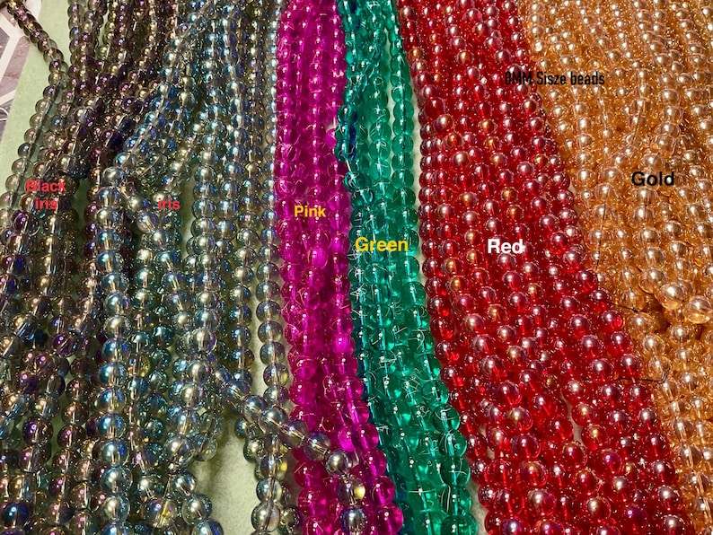 May include: Assortment of iridescent glass beads in various colours, including black, pink, green, red, and gold. The beads are 8mm in size.