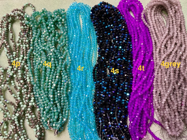 May include: Six strands of faceted glass beads in various colours, including grey, teal, light blue, dark blue, purple, and light grey. The strands are labelled with the letters 'p', 'q', 'r', 's', 't', and 'grey'.