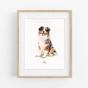 May include: Watercolor painting of a dog in a wooden frame. The dog is a mix of black, brown, and white, with a happy expression. The dog is sitting on a patch of green grass. The name "Abby" is written below the dog.