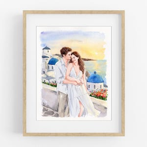 Könnte beinhalten: Ein gerahmtes Aquarellbild, das ein Paar zeigt, das sich vor einer Kulisse aus weißen Gebäuden mit blauen Kuppeln bei Sonnenuntergang umarmt. Die linke Person trägt ein helles Hemd und eine Hose, die rechte Person ein weißes Kleid.