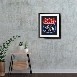 Puede incluir: Una impresión en blanco y negro enmarcada de un letrero de neón de la Ruta 66. El letrero es rojo, blanco y azul con fondo negro.