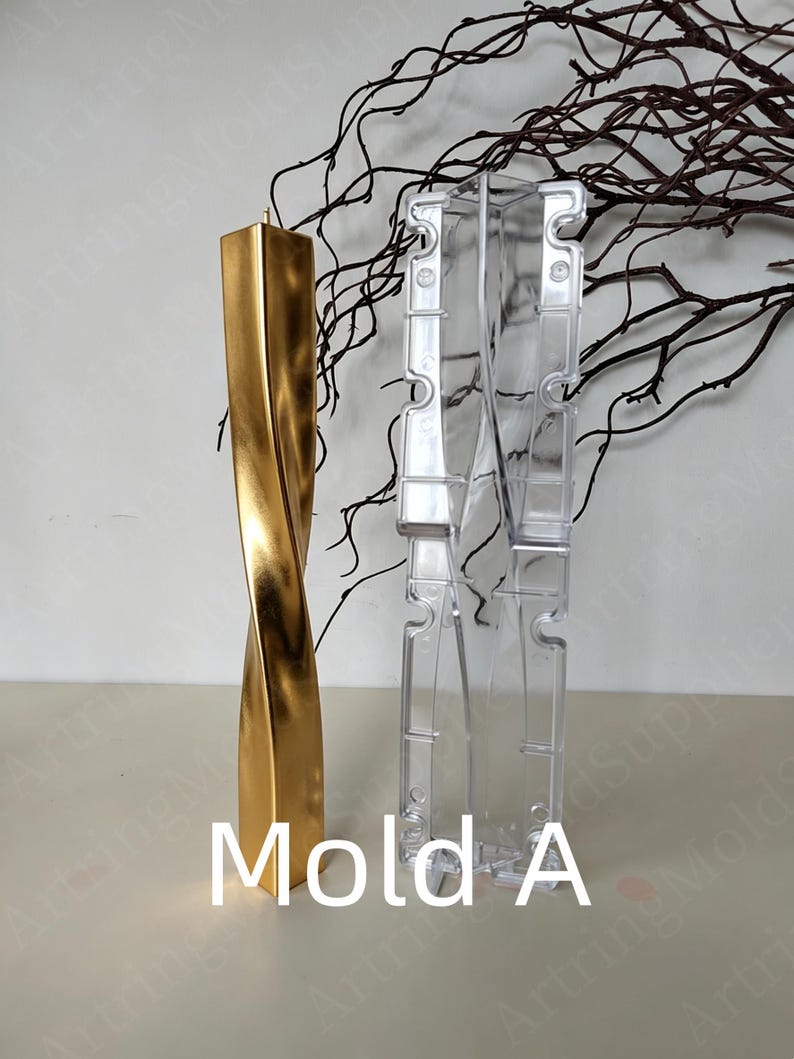 May include: A gold-coloured, twisted candle stands next to a clear plastic mould labelled "Mold A." The candle has a rectangular shape with a spiral design. The mould is designed to create candles. Decorative branches are in the background.