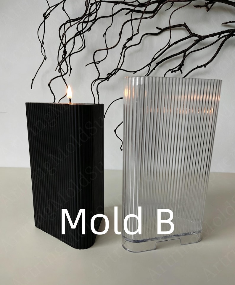 May include: A black, rectangular candle with a vertical ribbed design is lit, next to a clear, ribbed plastic mold. The text "Mold B" is printed in white. Decorative branches are in the background.