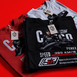 Könnte beinhalten: Drei T-Shirts in Rot, Schwarz und Weiß mit Rennsport-Motiv. Das schwarze Shirt zeigt "Checo Pérez" mit einer Rennwagen-Grafik und "SPEED 300 KM/H". Jedes Shirt hat ein Etikett mit einem Logo.