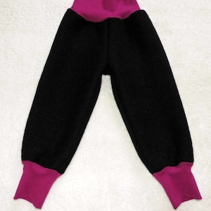 May include: Black fleece trousers with a pink waistband and cuffs. The trousers are loose fitting and have a casual style.
