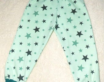 Puede incluir: Pantalones de bebé verde menta con un estampado de estrellas negras y turquesas. Los pantalones tienen una cintura y puños turquesa. La tela parece suave y cómoda, adecuada para el uso diario.