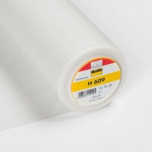 Puede incluir: Un rollo blanco de entretela termoadhesiva con una etiqueta amarilla que dice "H 609 100% PA 25 cm x 25 m".