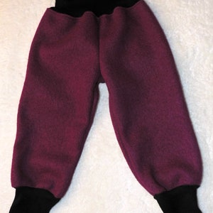 Könnte beinhalten: Bordeauxfarbene Fleecehose mit schwarzem elastischem Bund und Bündchen. Die Hose ist aus einem weichen, warmen Material gefertigt und perfekt für kaltes Wetter.