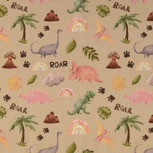 Könnte beinhalten: Beigefarbener Stoff mit einem sich wiederholenden Muster aus Dinosauriern, Palmen, Regenbogen, Sonnen, Vulkanen und Pfotenabdrücken. Das Wort "ROAR" ist in Schwarz gedruckt. Dinosaurier sind in Rosa-, Grün- und Grautönen gehalten.