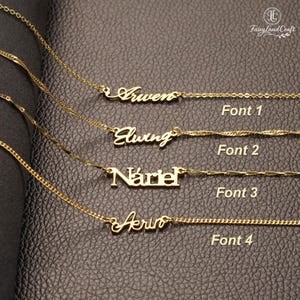 May include: Four gold-colored name necklaces with different fonts are displayed on a dark leather surface. The names are "Arwen", "Elwing", "Nariel", and "Arin". Each necklace has a delicate chain. The image also includes the text "Font 1", "Font 2", "Font 3", and "Font 4".
