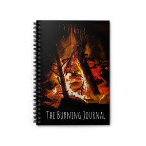 May include: A spiral bound journal with a black cover featuring a photograph of a campfire with flames and sparks. The text "THE BURNING JOURNAL" is printed in white at the bottom of the cover.