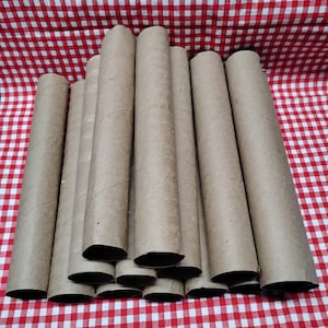 May include: A collection of cylindrical cardboard tubes, arranged in a slightly angled pile. The tubes are a natural brown color and appear to be made from recycled materials. The background is a red and white checkered pattern.