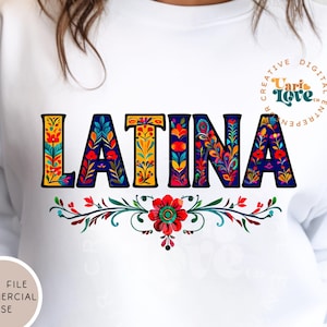 May include: A white sweatshirt featuring the word "LATINA" in colourful, patterned letters. The letters are outlined in black and have a floral design. The text "Creative Digital Entrepreneur" is in a circle on the right side of the sweatshirt.