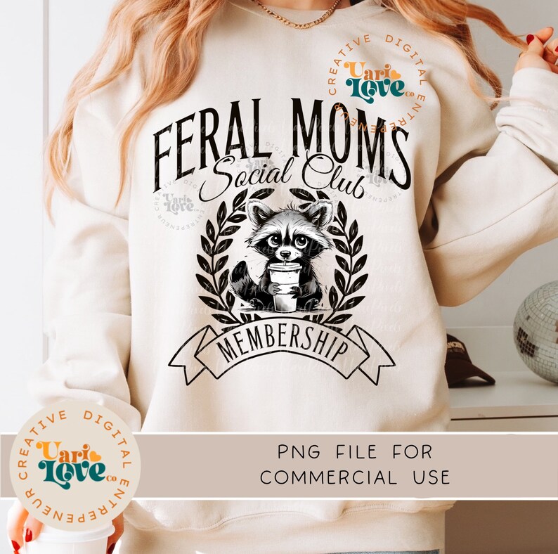 May include: A white sweatshirt with the text "Feral Moms Social Club" and a black and white illustration of a raccoon holding a cup of coffee. The raccoon is surrounded by a wreath of leaves. Below the raccoon is a banner with the text "Membership".