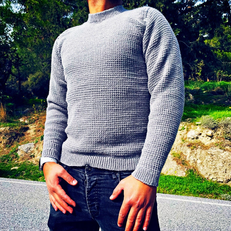 May include: A gray waffle knit sweater with a mock neck and long sleeves.