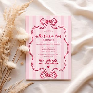 May include: A pink and white striped Galentine's Day brunch invitation. The invitation features a decorative red bow design and text that reads "Join us for a Galentine's Day Brunch" with event details. The invitation is on a white surface with dried flowers.