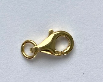 May include: A gold-toned lobster clasp for jewelry making. The clasp is a common type of closure for necklaces, bracelets, and other jewelry.