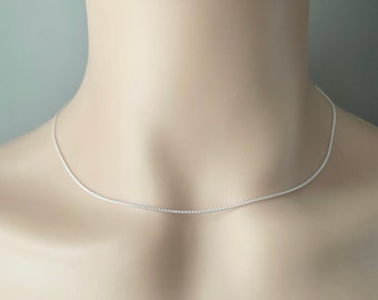 May include: A silver chain necklace on a white mannequin.