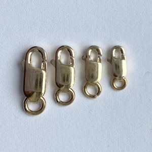 May include: Four gold-toned lobster clasps of varying sizes. The clasps are arranged in order of size from left to right.