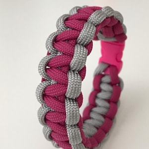 May include: A pink and grey paracord bracelet with a pink plastic clasp.