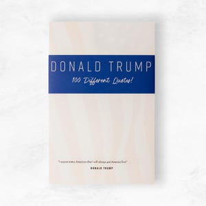 May include: A book with a light beige cover and a blue band across the middle. The text "DONALD TRUMP 100 Different Quotes!" is printed on the blue band. A quote by Donald Trump is printed at the bottom.