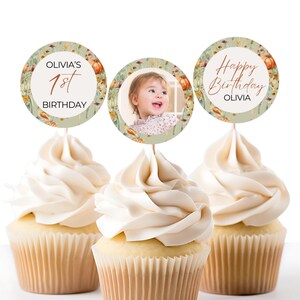May include: Three cupcake toppers with a fall theme. The toppers feature a photo of a young girl, the text "Olivia's 1st Birthday" and the text "Happy Birthday Olivia".