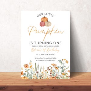 Puede incluir: Una invitaci&oacute;n blanca con un gr&aacute;fico de calabaza dorada y el texto "Our Little Pumpkin is Turning One". La invitaci&oacute;n tambi&eacute;n incluye el texto "Please join us to celebrate Olivia's 1st Birthday", "October 27th at 3pm", "123 Anywhere St, Any City, ST 12345", y "Please RSVP at +123-456-7890". La invitaci&oacute;n est&aacute; decorada con una ilustraci&oacute;n de acuarela de flores y hojas de oto&ntilde;o.