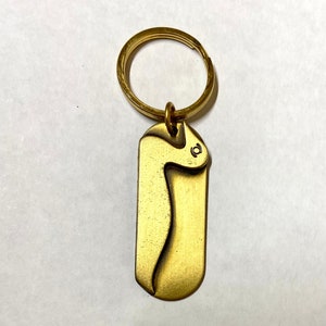 May include: A gold-colored metal keychain with a key ring and a decorative tag shaped like a stylized letter 'S'.