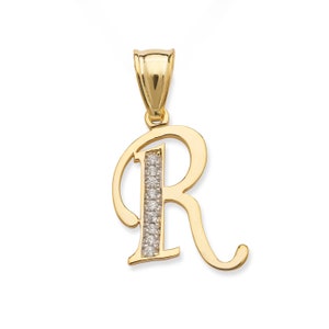 Puede incluir: Un colgante de oro con la letra 'R' con una fila de diamantes transparentes en el centro de la letra.