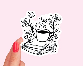 May include: Black and white line art sticker of a cup of coffee on top of a stack of books with flowers and hearts around it.