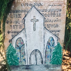 Puede incluir: Pintura hecha a mano de una iglesia blanca con una cruz, sobre un fondo de partituras antiguas. La obra presenta vidrieras y dos &aacute;rboles de Navidad verdes. El texto "O Holy Night" es visible.