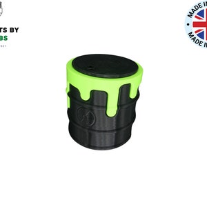 May include: A black and green 3D printed container with a dripping green top. The container has a circular lid and a symbol on the side.