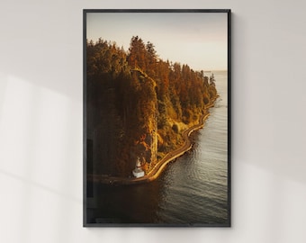 May include: A framed photograph of a rocky coastline with a winding road leading to a small white building. The coastline is covered in lush green trees and the water is a deep blue. The photo is taken from a high angle, giving a panoramic view of the scene.