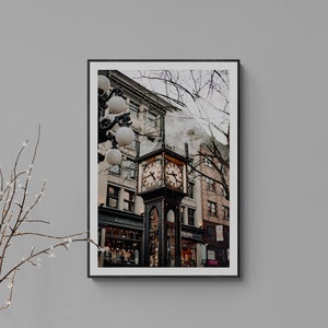 May include: A black and white photograph of a clock tower in a city. The clock tower is made of brick and has a large clock face with Roman numerals. The tower is surrounded by buildings and trees.