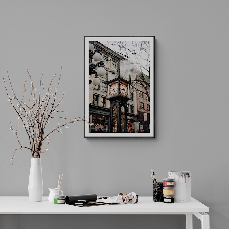 K&ouml;nnte beinhalten: Ein Schwarzwei&szlig;foto eines Uhrturms in einer Stadt. Der Uhrturm ist aus Ziegeln gebaut und hat ein gro&szlig;es Zifferblatt mit r&ouml;mischen Ziffern. Der Turm ist von Geb&auml;uden und B&auml;umen umgeben.