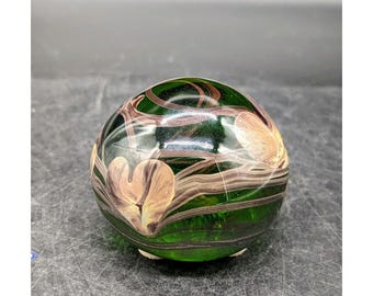 May include: A green glass paperweight with brown and white swirls and a heart design.