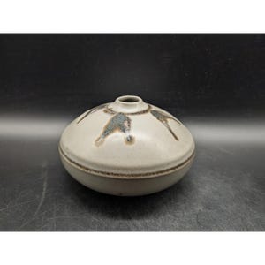 May include: A set of three ceramic mugs with a speckled, matte finish. The mugs are in shades of cream, light brown, and dark brown. Each mug has a simple, minimalist design, perfect for coffee or tea.