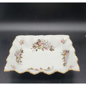 May include: White rectangular serving dish with a scalloped edge and gold trim. The dish is decorated with a floral and fruit pattern in pink, green, and brown. The dish is approximately 10 inches long and 6 inches wide.