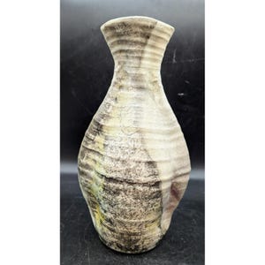 May include: A handcrafted ceramic vase with a textured, ridged surface. The vase features a neutral color palette with shades of beige, brown, and hints of yellow and red. The vase has a wide base and a narrow neck.