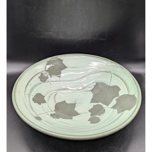 May include: A light green ceramic plate with a swirling design and gray leaf silhouettes.