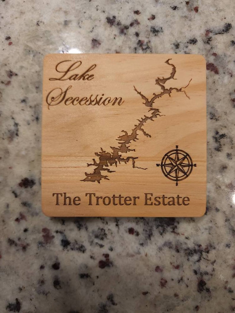 Pu&ograve; includere: Un sottobicchiere in legno con una mappa del lago Secession e il testo "The Trotter Estate".