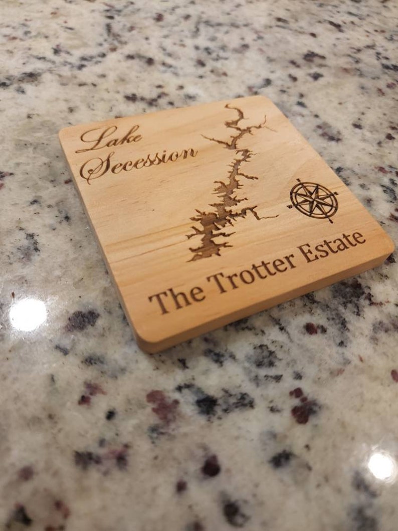 Pu&ograve; includere: Un sottobicchiere in legno con una mappa incisa a laser del lago Secession e il testo "The Trotter Estate".