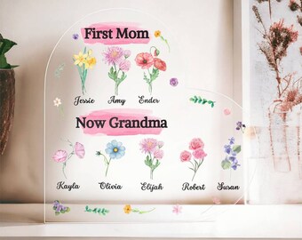 May include: A heart-shaped acrylic plaque with watercolor flowers and the text "First Mom Now Grandma". The plaque features the names of children: Jessie, Amy, Ender, Kayla, Olivia, Elijah, Robert, and Susan.