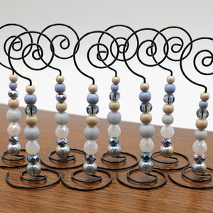 Puede incluir: Diez soportes de adornos con cuentas con una base de alambre en espiral. Las cuentas son en tonos de azul, dorado y blanco.