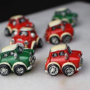 Könnte beinhalten: Eine Sammlung von Miniatur-Spielzeugautos in Rot und Grün. Die Autos sind alle vom gleichen Modell, aber einige haben ein weißes Dach und andere ein schwarzes Dach.