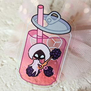 May include: A clear sticker depicting a cartoon character inside a pink drink can with a straw. The character is white with a black face and is holding a golden spoon. Blackberries and ice cubes are also inside the can.