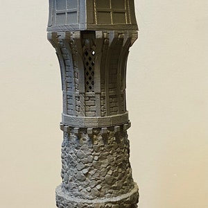 Puede incluir: Una torre en miniatura gris impresa en 3D con una base de piedra, ventanas y un techo puntiagudo. Dos figuras en miniatura están cerca. La torre mide aproximadamente 25 cm de altura. Adecuada para juegos de mesa o como pieza decorativa.