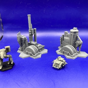Pode incluir: Uma coleção de estruturas e veículos em miniatura cinzentos, incluindo edifícios com detalhes industriais, um mech e um tanque. Os modelos estão sobre um fundo azul, mostrando um tema futurista ou de ficção científica.