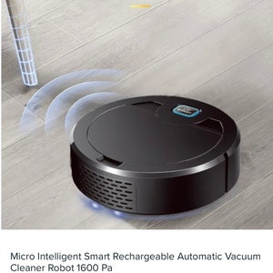 以下が含まれることがあります： 明るい木製の床に置かれた、黒い円形のロボット掃除機。 このデバイスは、上部パネルと側面通気孔を備えたロープロファイルです。 画像は、掃除機のクリーニングパスを曲線で示しています。 下部のテキストは次のとおりです: Micro Intelligent Smart Rechargeable Automatic Vacuum Cleaner Robot 1600 Pa.